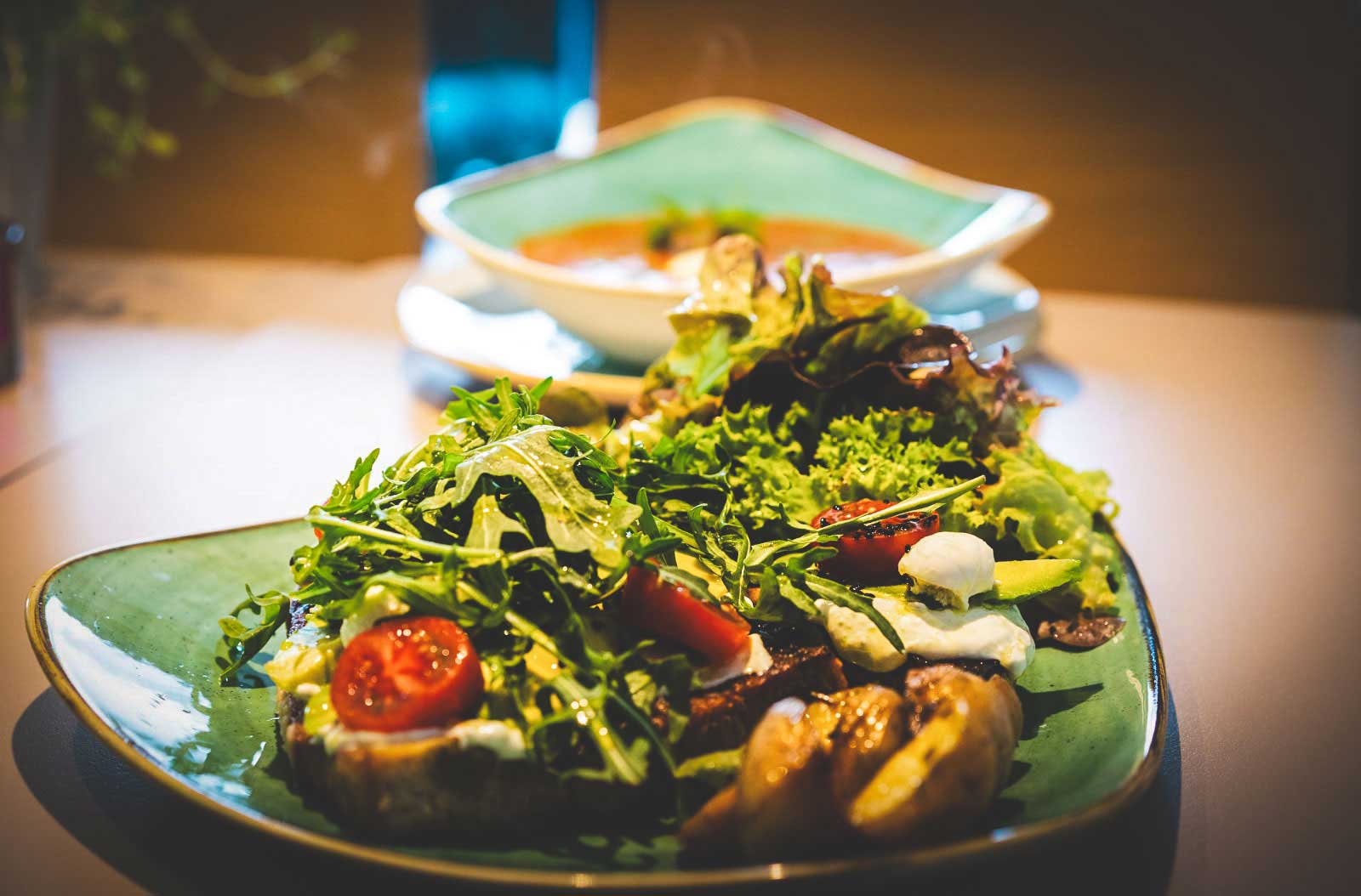 Brotmahlzeit mit geröstetem Brot, Avocado, Tomaten, Ruccola mit Ofenkartoffeln und Salat